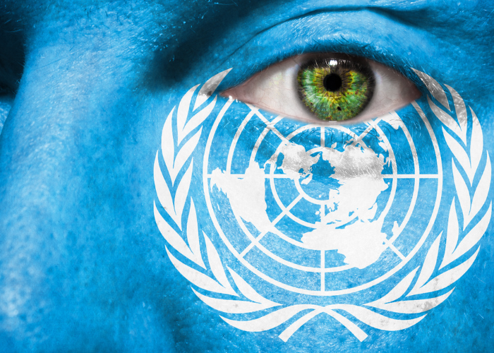 Image of a face focusing on the person's left eye. The United Nations logo is painted below the eye.